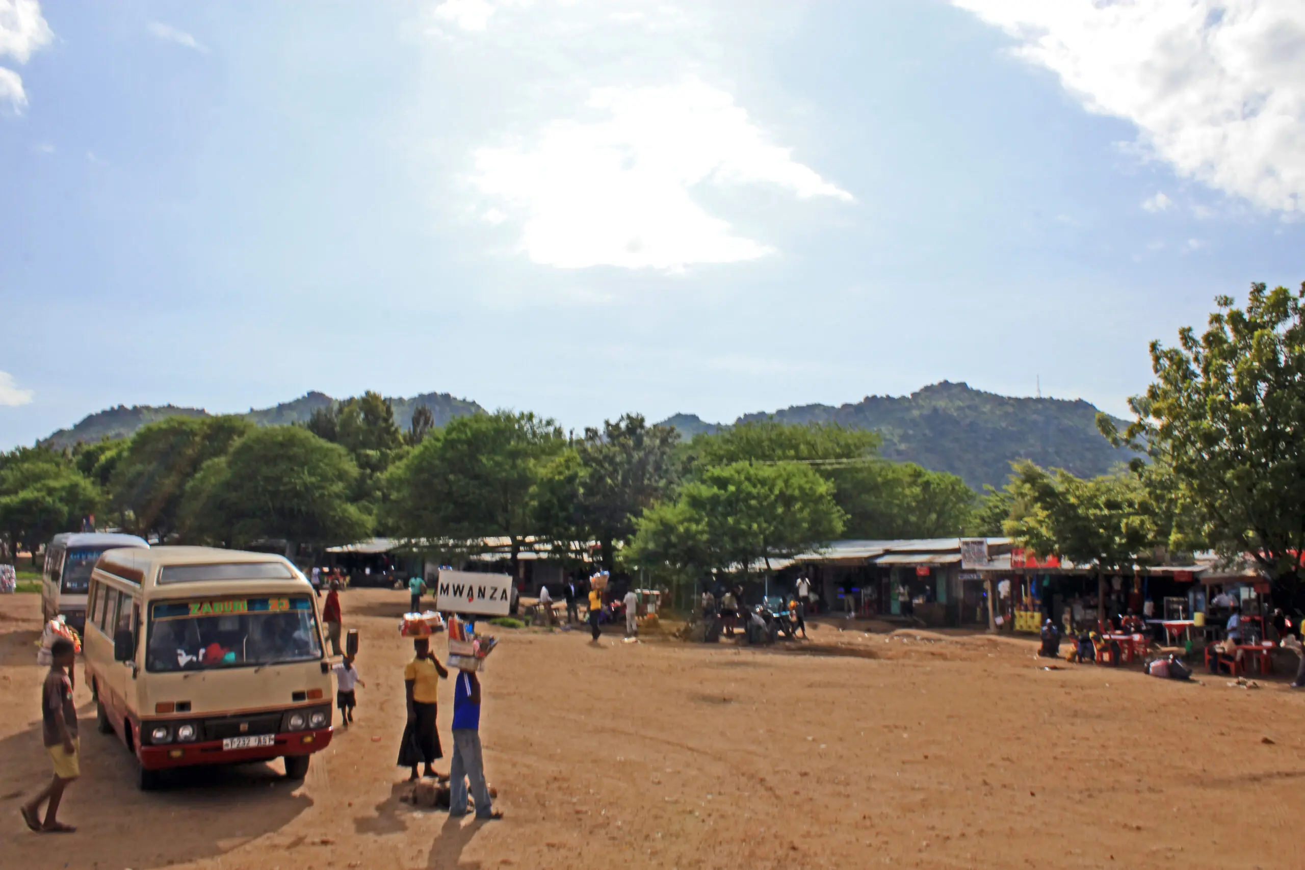 Bus stop with people and surrounding hills.