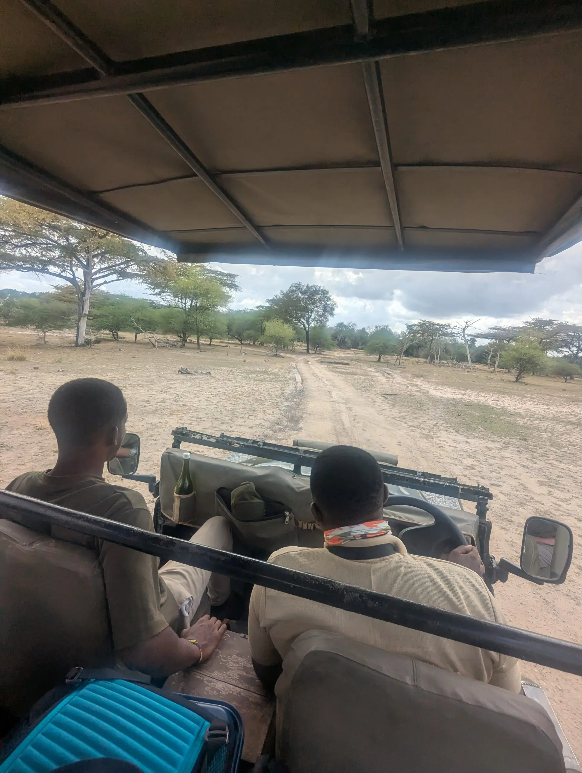 Safari vehicle driving on dirt road.