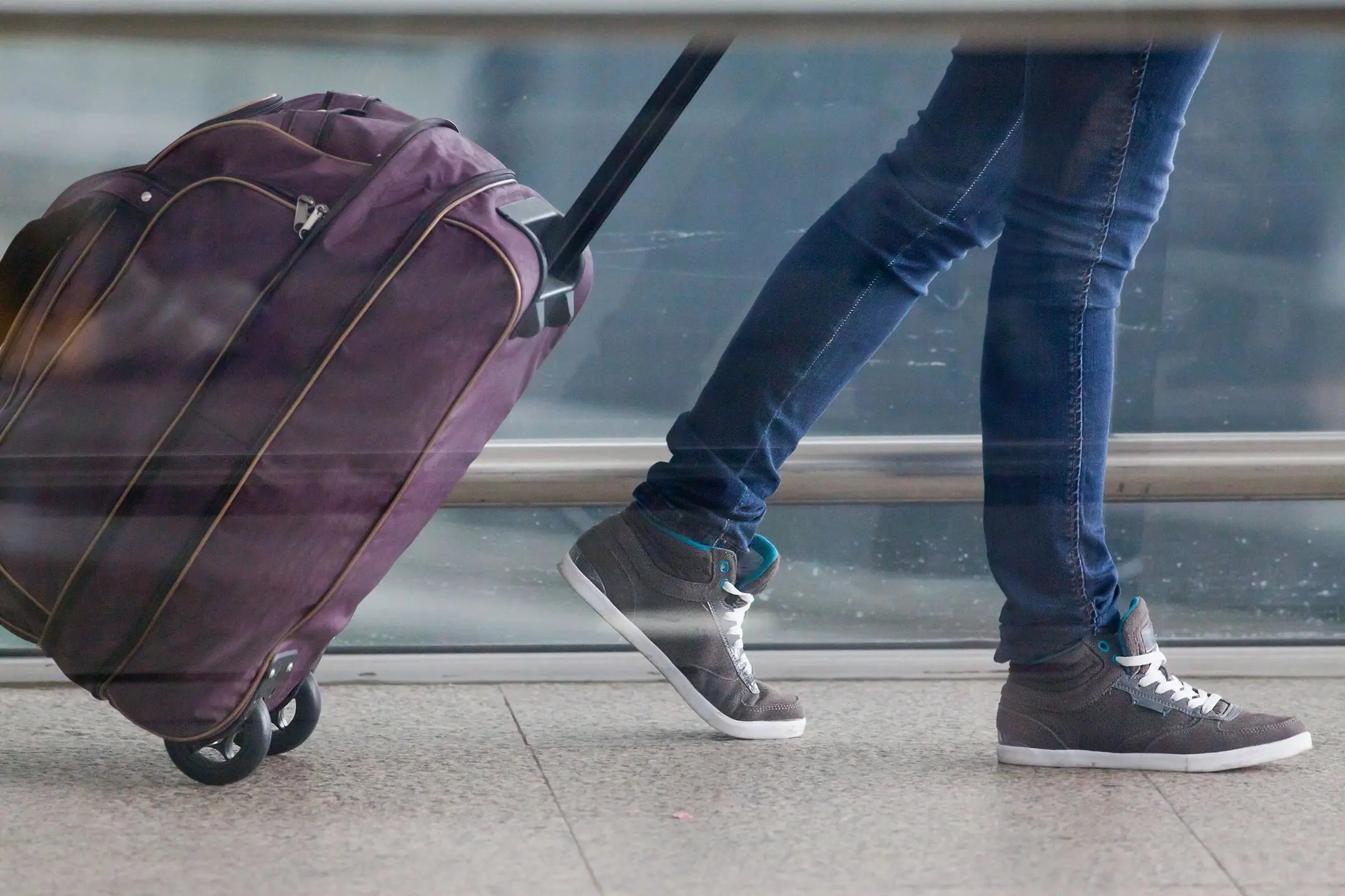 Traveler pulling purple suitcase at airport.