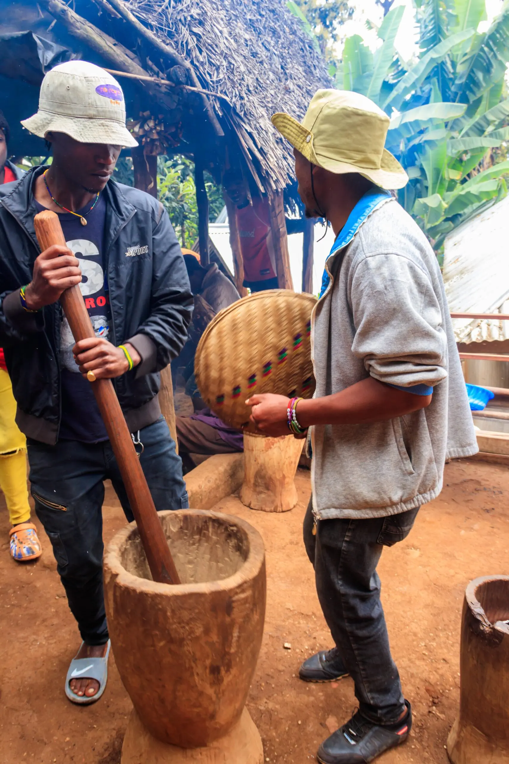Two people grinding with mortar and pestle.