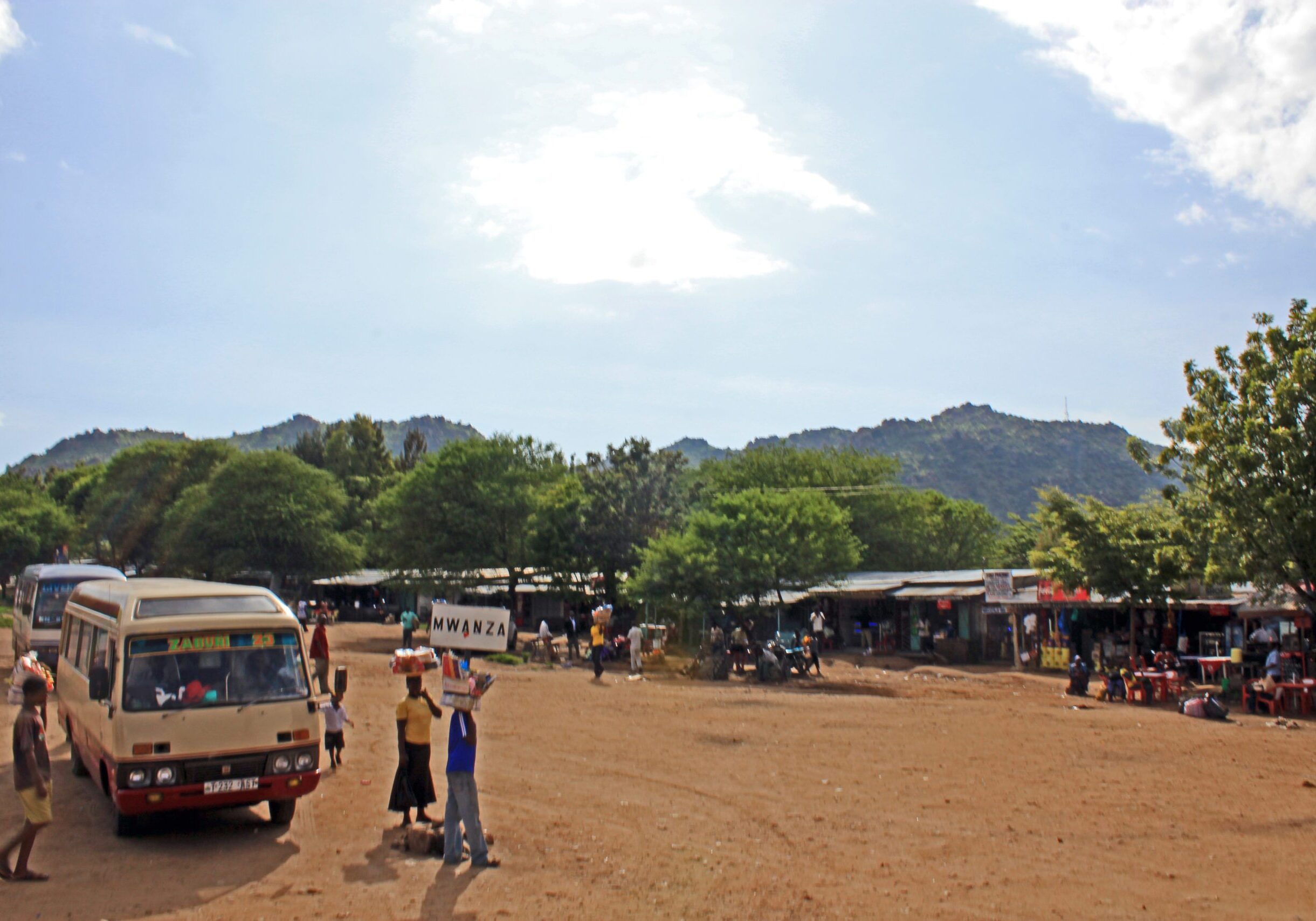 Bus stop with people and surrounding hills.