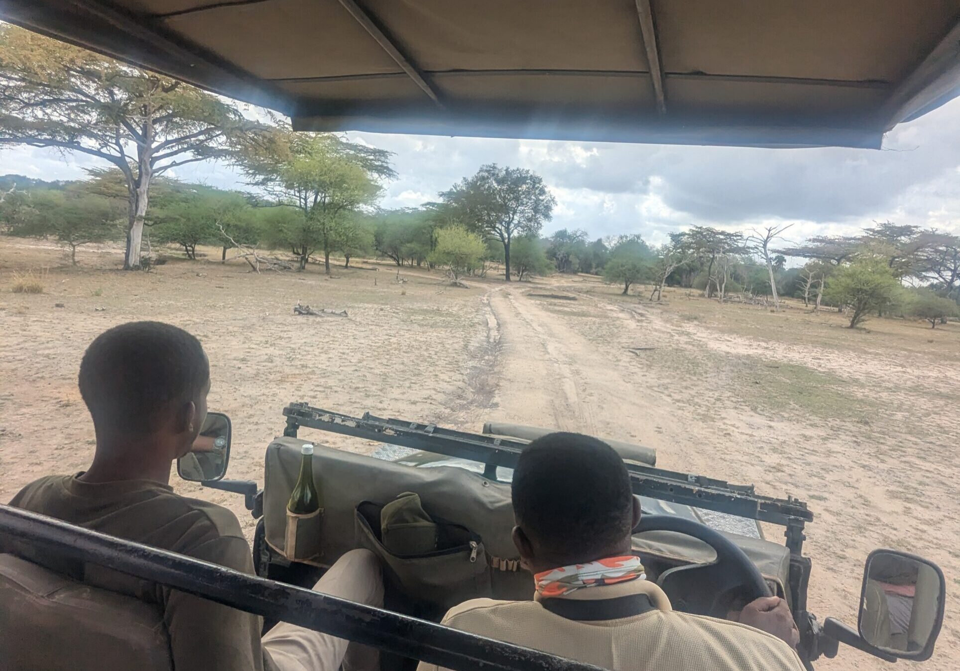 Safari vehicle driving on dirt road.