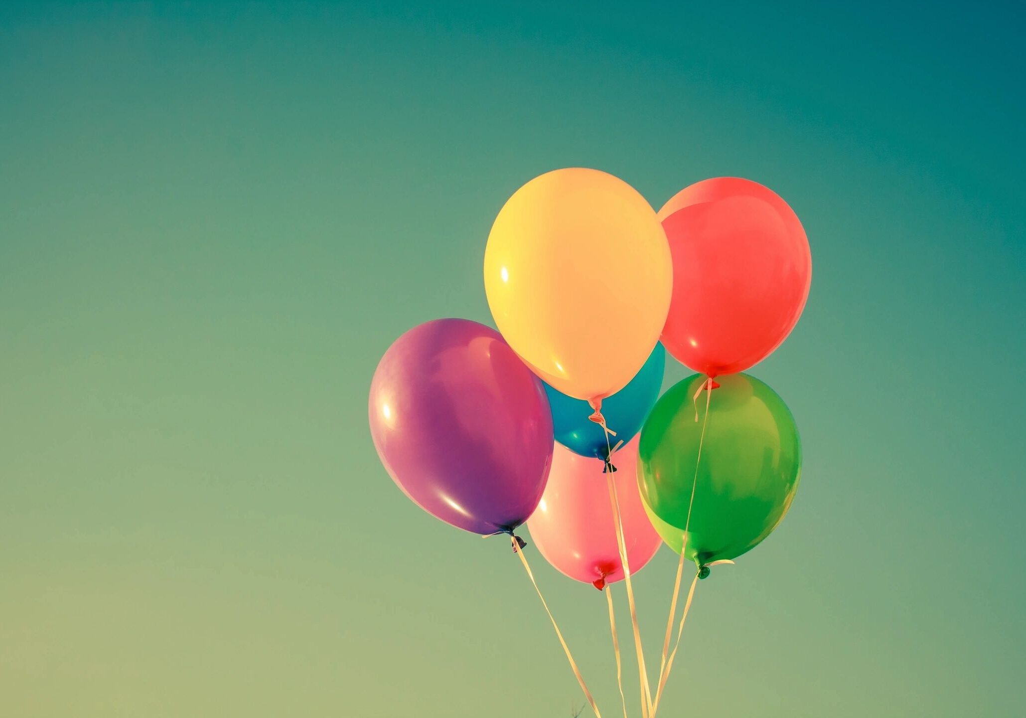 Colorful balloons floating against clear sky.