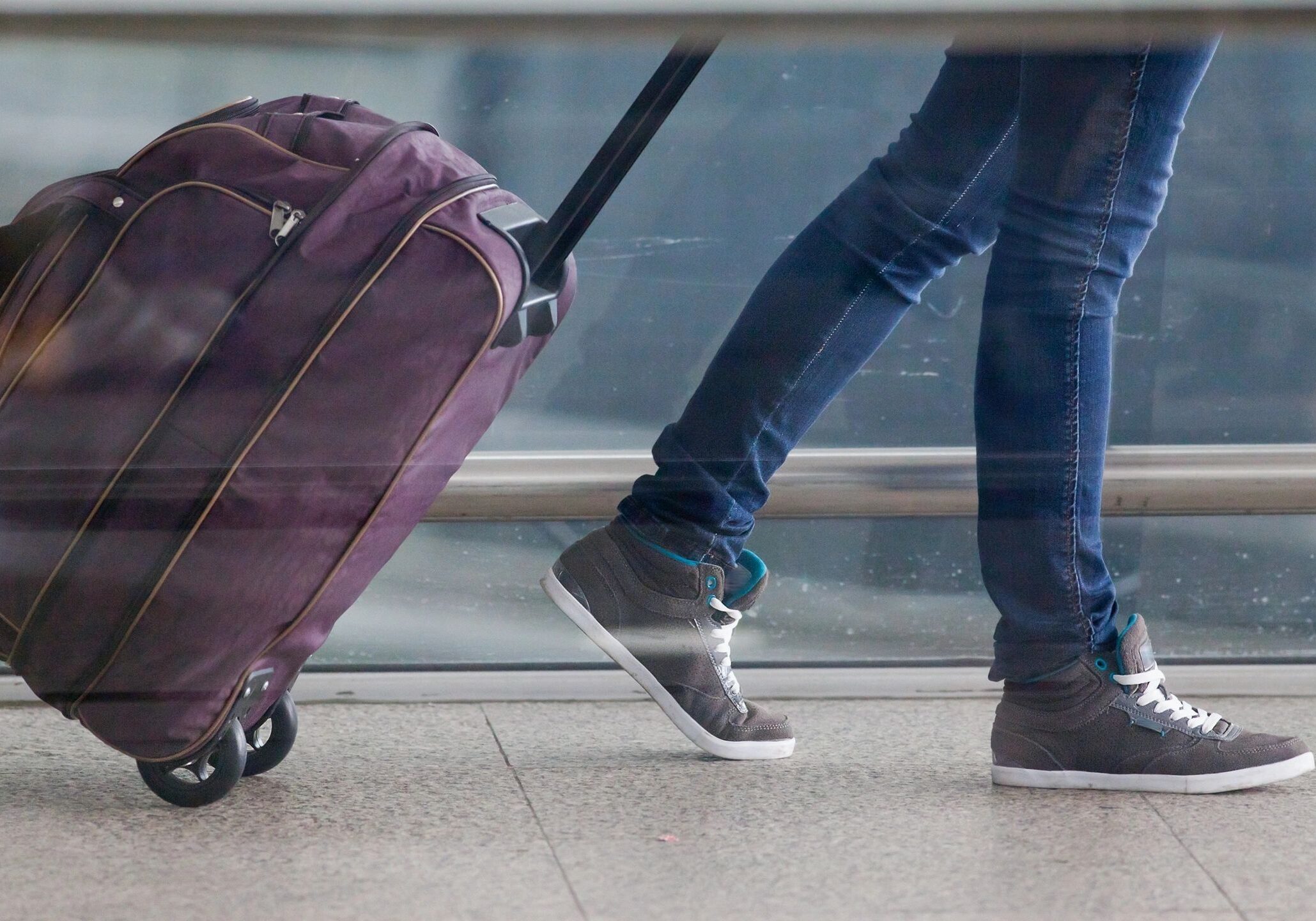 Traveler pulling purple suitcase at airport.