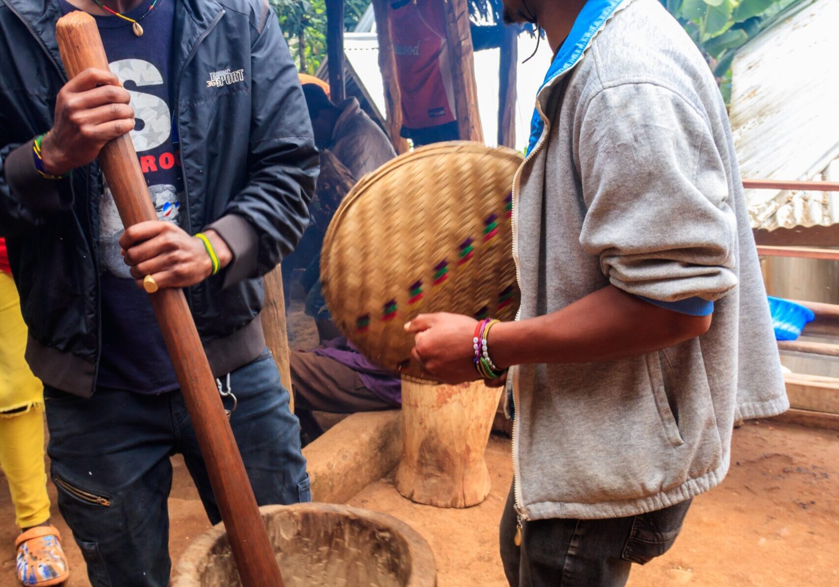 Two people grinding with mortar and pestle.